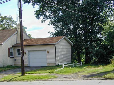 The abandoned road with the new street sign. The marker is located just past the far end of the fence.