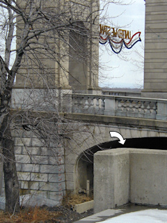 The mark is on the corner of the concrete wall. The Market Street Bridge is in the background.