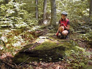 Zhanna on the boulder, pointing to the mark.