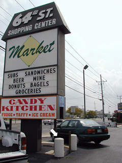 The 64th Street Shopping Center sign and guard posts, with the location of the mark indicated.