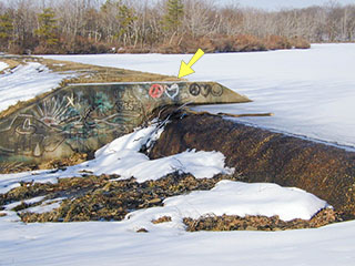 Looking northeast at the spillway and reservoir. The location of the mark is indicated.