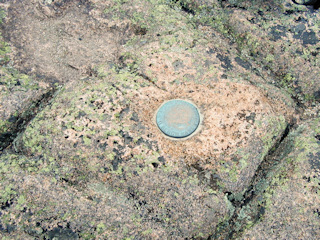 An eyelevel view of the disk set in Cadillac Mountain's weathered pink granite.