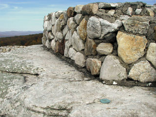 The reference mark is set very close to the rock wall surrounding the overlook.