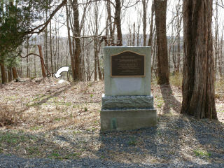 Standing on Old Mine Road, looking at the face of the monument. The survey mark is indicated in the background.