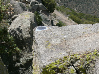 Eyelevel view of the reference mark disk set into the corner of a large chunk of bedrock.