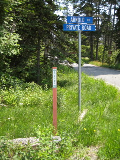 Monument, witness post and signs at the intersection of Arnold Road and Lighthouse Road, which leads down to Bass Harbor Head Lighthouse.