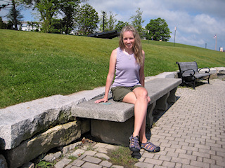 Zhanna enjoys the sunshine while lounging on a bench (with a benchmark) near the harbor.