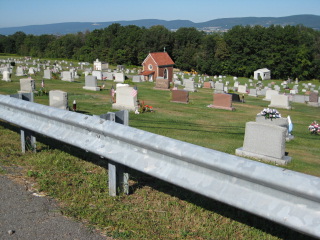 Looking W over cemetery, toward small chapel; West Mountain in background.