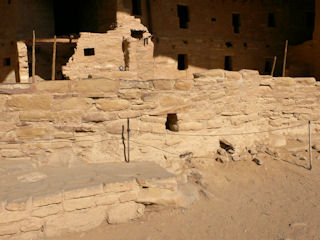 A sunlit view of the cliff dwelling, and the disk on the step in the foreground.