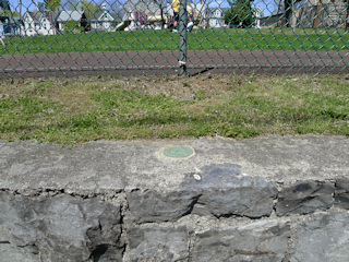 Eyelevel view of the reference mark disk set into the stone wall.