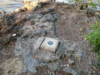 Eyelevel view of the disk on the concrete monument near the water’s edge.