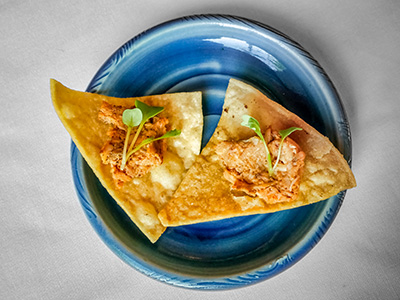 An amuse-bouche of smoked chicken with chipotle on a corn chip