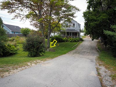 Boulder, house, and driveway viewed from the highway