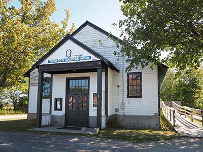 The disk is on the west face of the southwest corner of the grange hall.